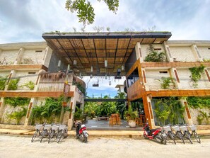 A building with a covered entrance, outdoor seating, and bicycles parked in front. - Xperience Tulum 25 (Tulum)