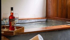 A spa area with a wooden bench, a bottle of Aperol, two glasses, and rolled towels. - Xperience Tulum 25 (Tulum)