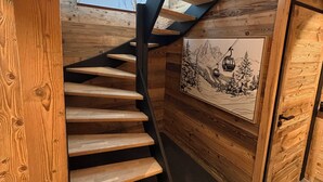 A wooden staircase with a black metal handrail, a wooden door, and a framed picture on the wall. - Luxury 115-square-meter chalet in a ski resort, ideal for two families (8–10 people) (Saint-Pierre-dels-Forcats)