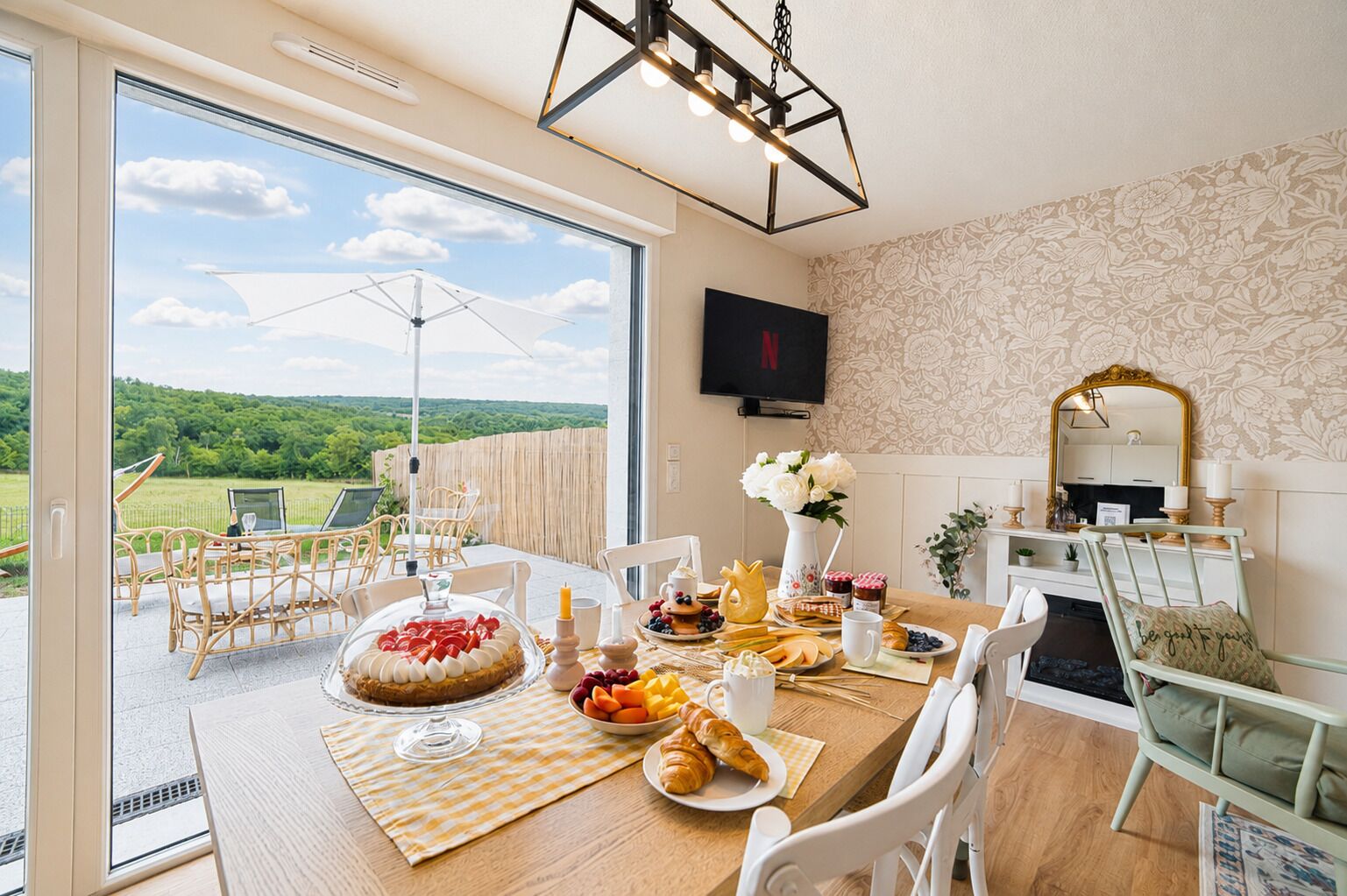 Un coin repas avec une table mise pour le petit-déjeuner, une vue sur l’extérieur et un téléviseur fixé au mur.