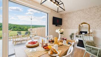 Un comedor con una mesa lista para el desayuno, vistas al exterior y un televisor montado en la pared.