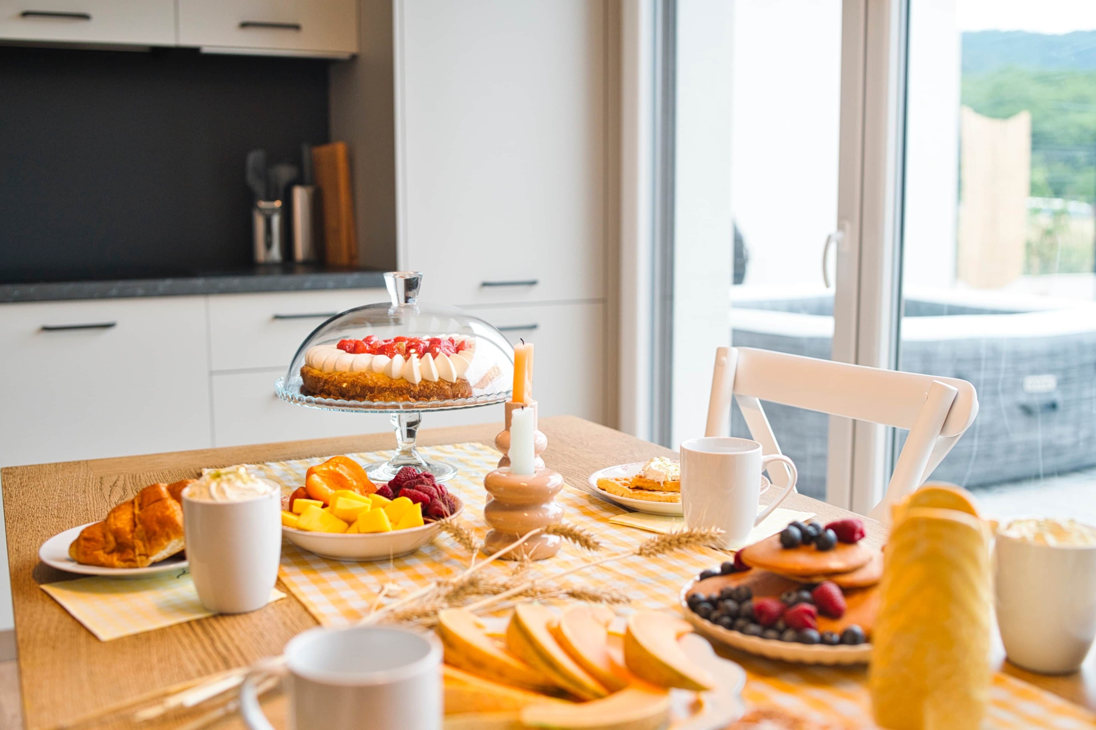 Een ontbijttafel met diverse etenswaren, een koffiekop en een kaars.