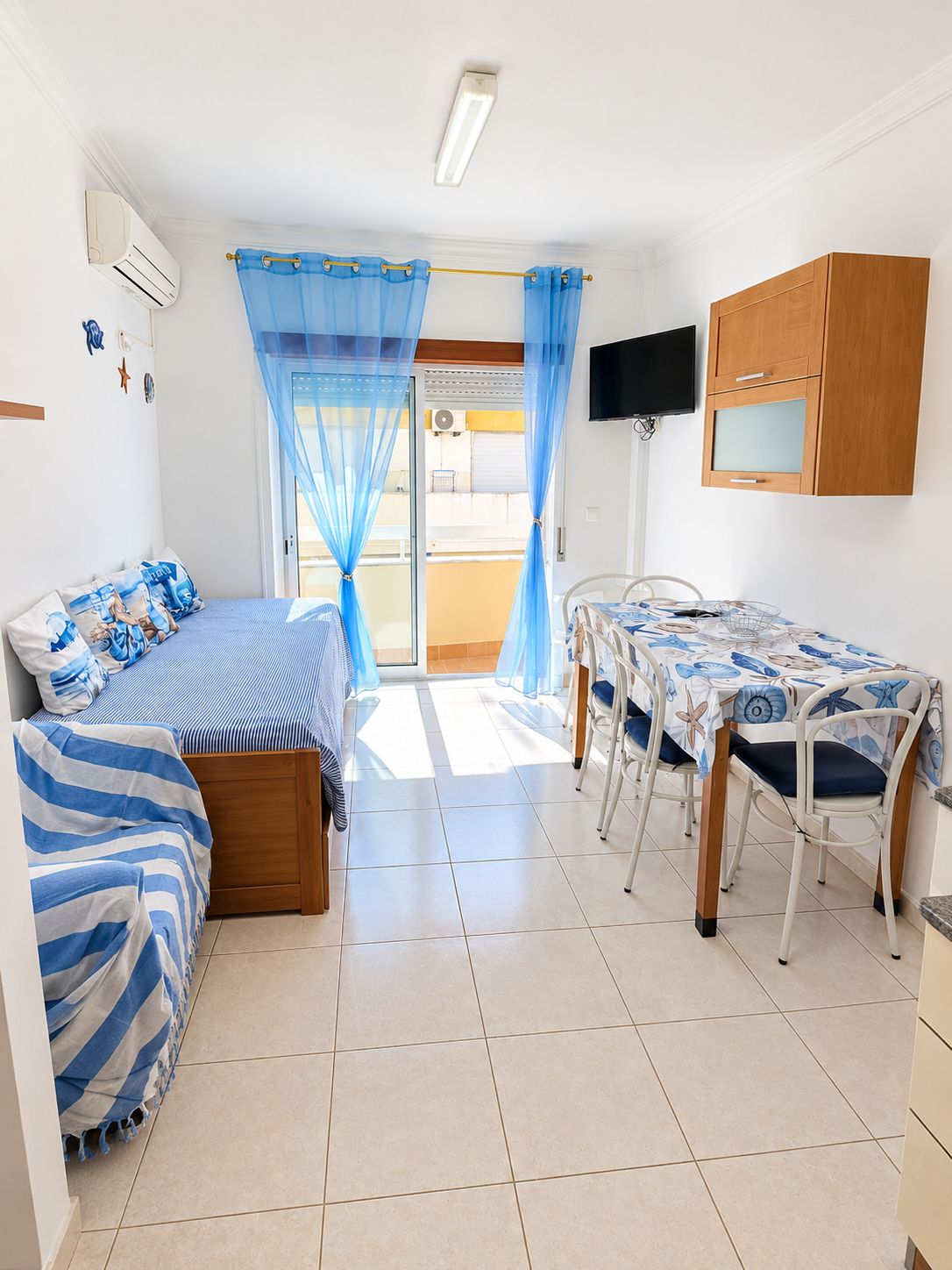 A room with a bed, a table with chairs, a television, and a wardrobe.