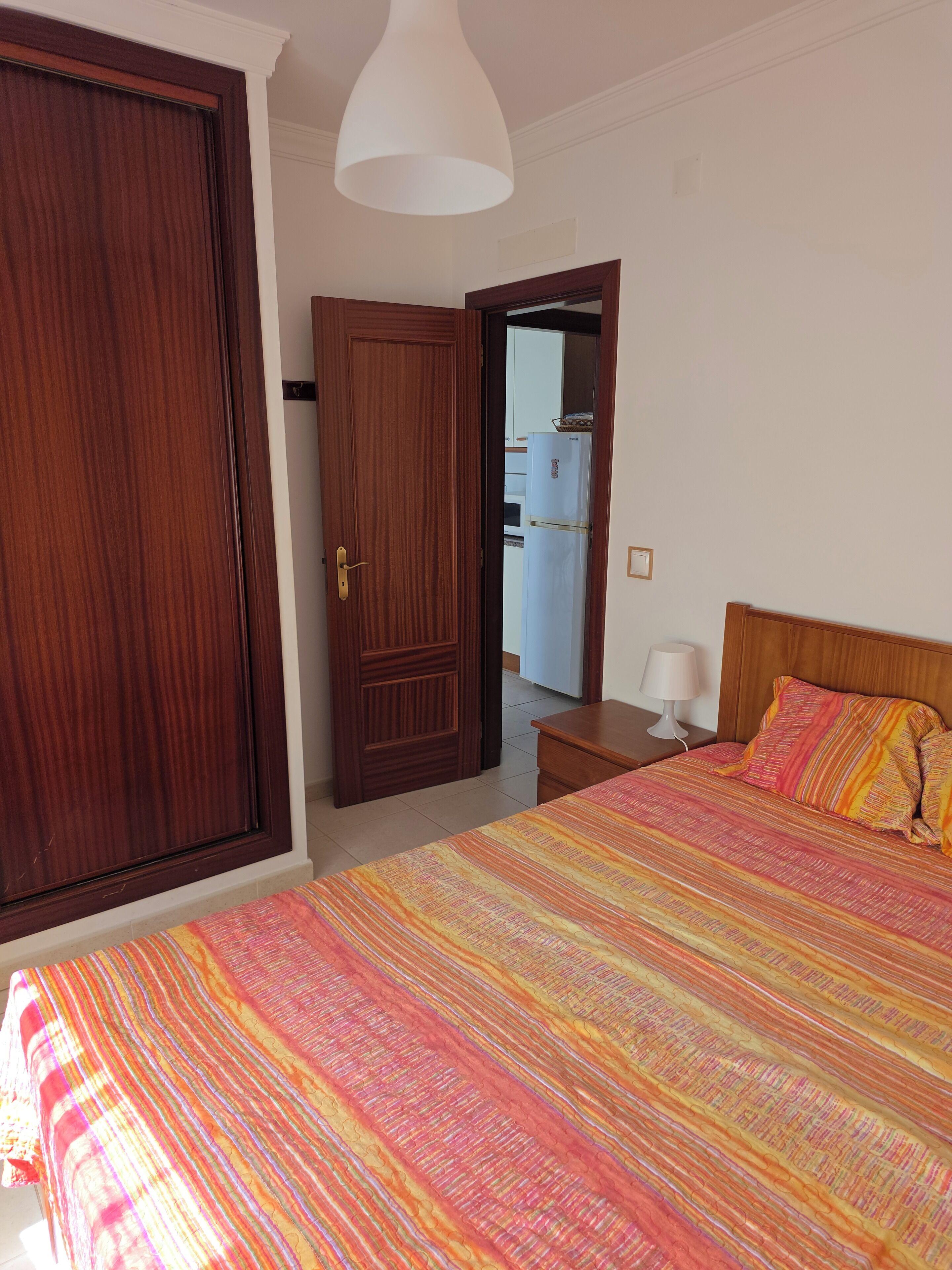 Une chambre d’hôtel avec un lit, une armoire, une porte et une lampe.