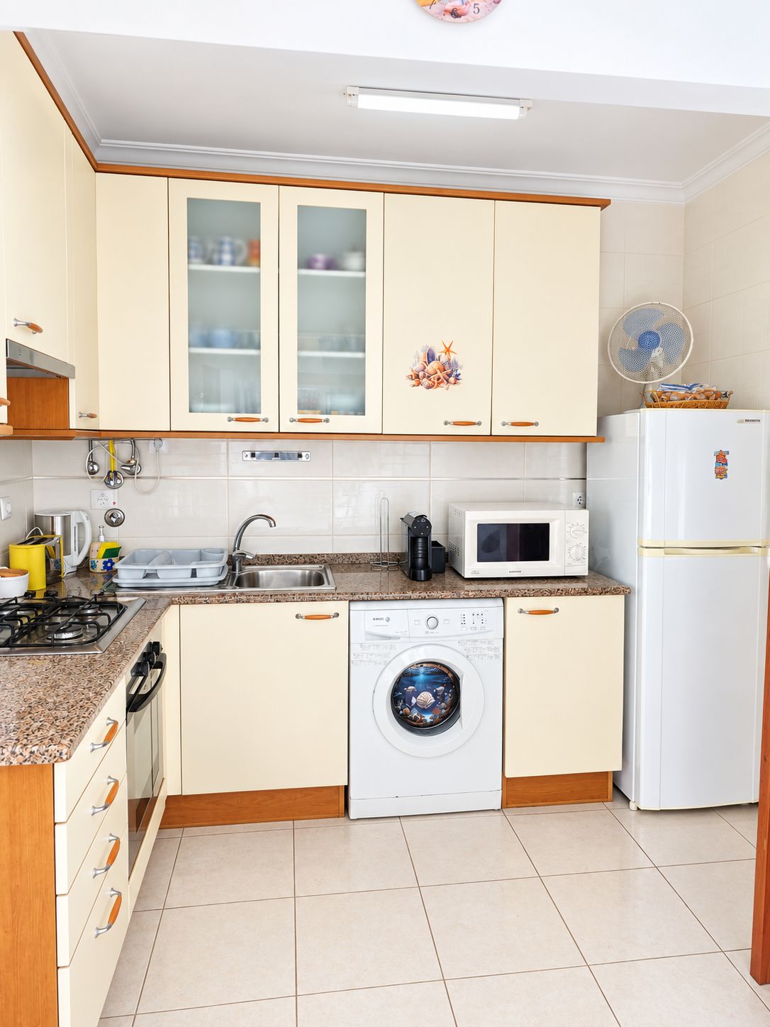 A compact kitchen with a gas stove, microwave, sink, and a washing machine.