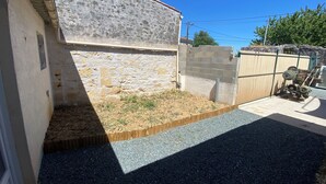 A courtyard with a stone wall, a wooden fence, and a gravel path. - Air-conditioned house in an ideal location (Montpellier-de-Médillan)