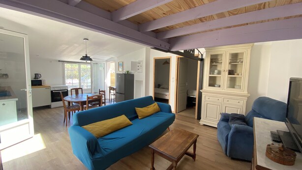 A living room with a blue sofa, wooden coffee table, and a TV stand. - Air-conditioned house in an ideal location (Montpellier-de-Médillan)