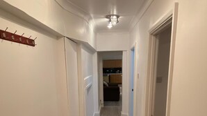 Un pasillo con suelo de madera, paredes blancas y una lámpara en el techo.