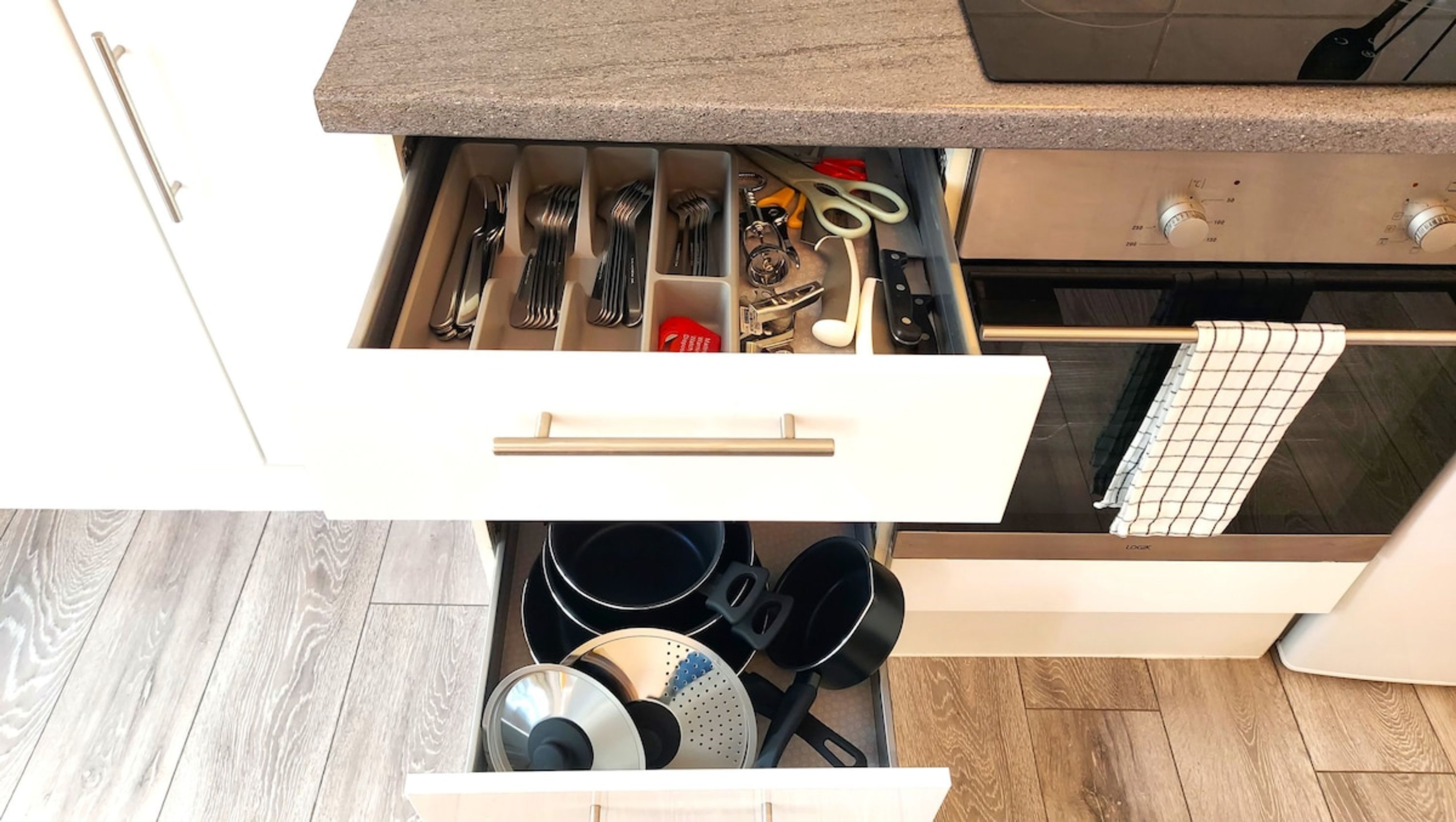 A kitchen drawer with utensils, a cutting board, and cookware.