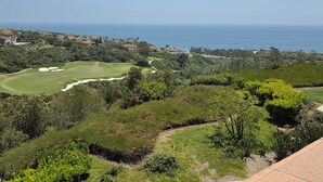 Un parcours de golf offrant une vue sur l’océan, avec des immeubles d’habitation en arrière-plan.
