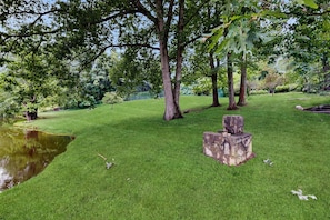 A well-maintained grassy area with trees and a small pond.