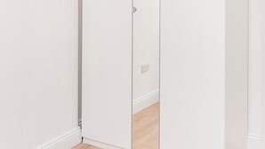 Une armoire blanche dotée d’un grand miroir sur toute sa hauteur.