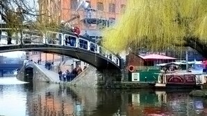 Eine Steinbrücke über Wasser, mit einem Boot am Ufer.