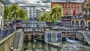 Ein Kanal mit einer Brücke, Gebäuden und einem roten Kran im Hintergrund.