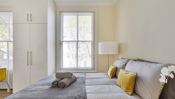 Ein Schlafzimmer mit einem Bett, einem Fenster, einer Lampe und einem Sessel.
