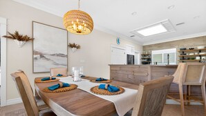 A dining area with a wooden table, chairs, and a hanging light fixture. - Waterfront Home with Pool & Dock (Siesta Key)