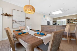 A dining area with a wooden table, chairs, and a hanging light fixture. - Waterfront Home with Pool & Dock (Siesta Key)
