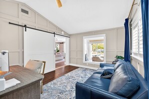A modern living room with a sofa, a dining table, and a view of the outdoors. - Waterfront Home with Pool & Dock (Siesta Key)