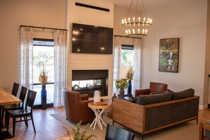 A modern living room with a fireplace, a large TV, and comfortable seating. - 1BR Condo w/ Private Balcony & Full Kitchen (Branson)
