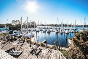Ein Yachthafen mit zahlreichen Schiffen, Holzstegen und blauem Himmel.