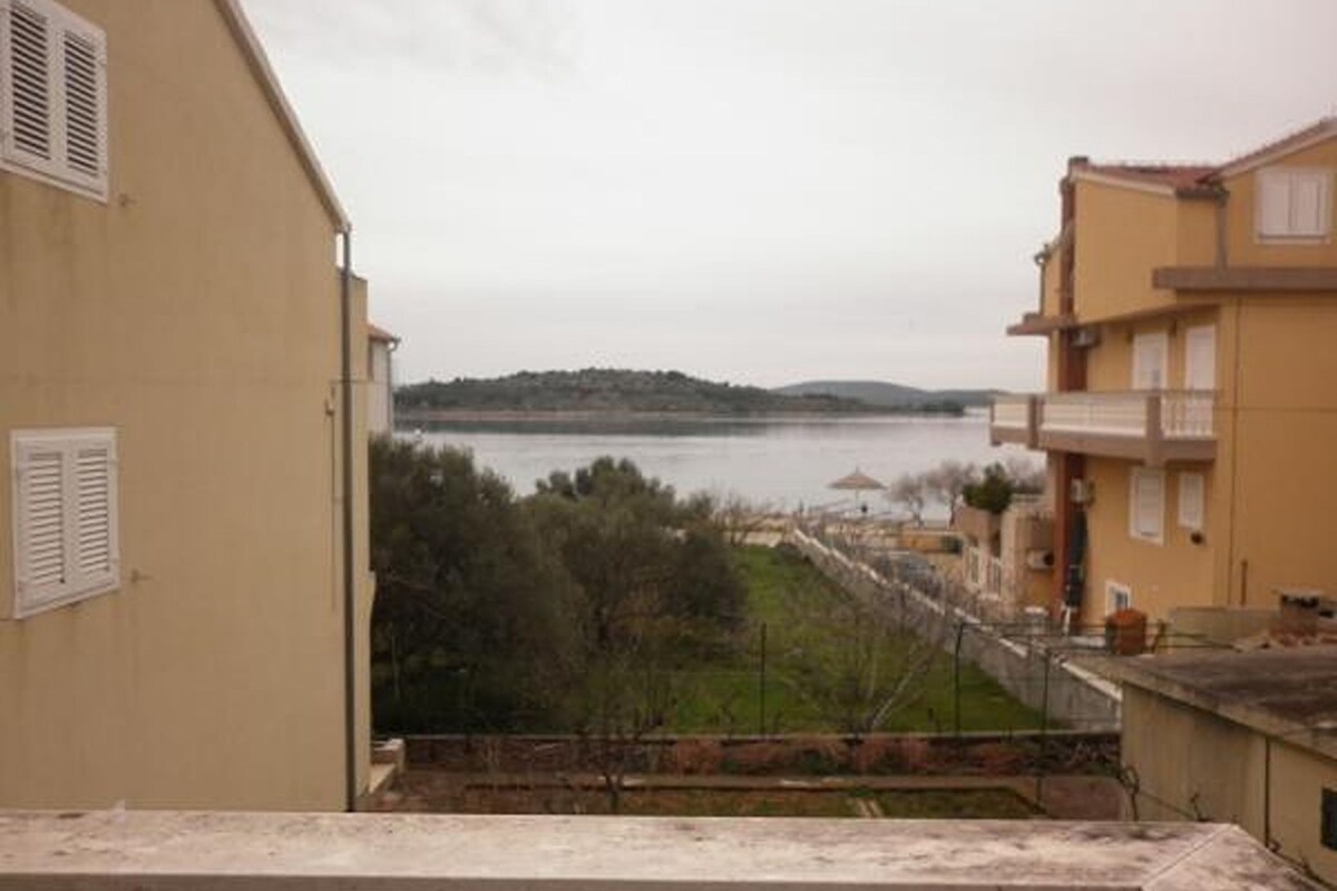 A building with a view of a body of water and hills in the distance.