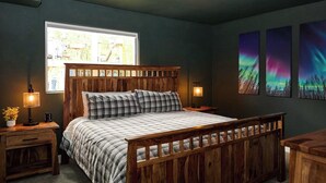 Una camera da letto con un letto di legno, due comodini, una finestra e tre opere d'arte a tema aurora.