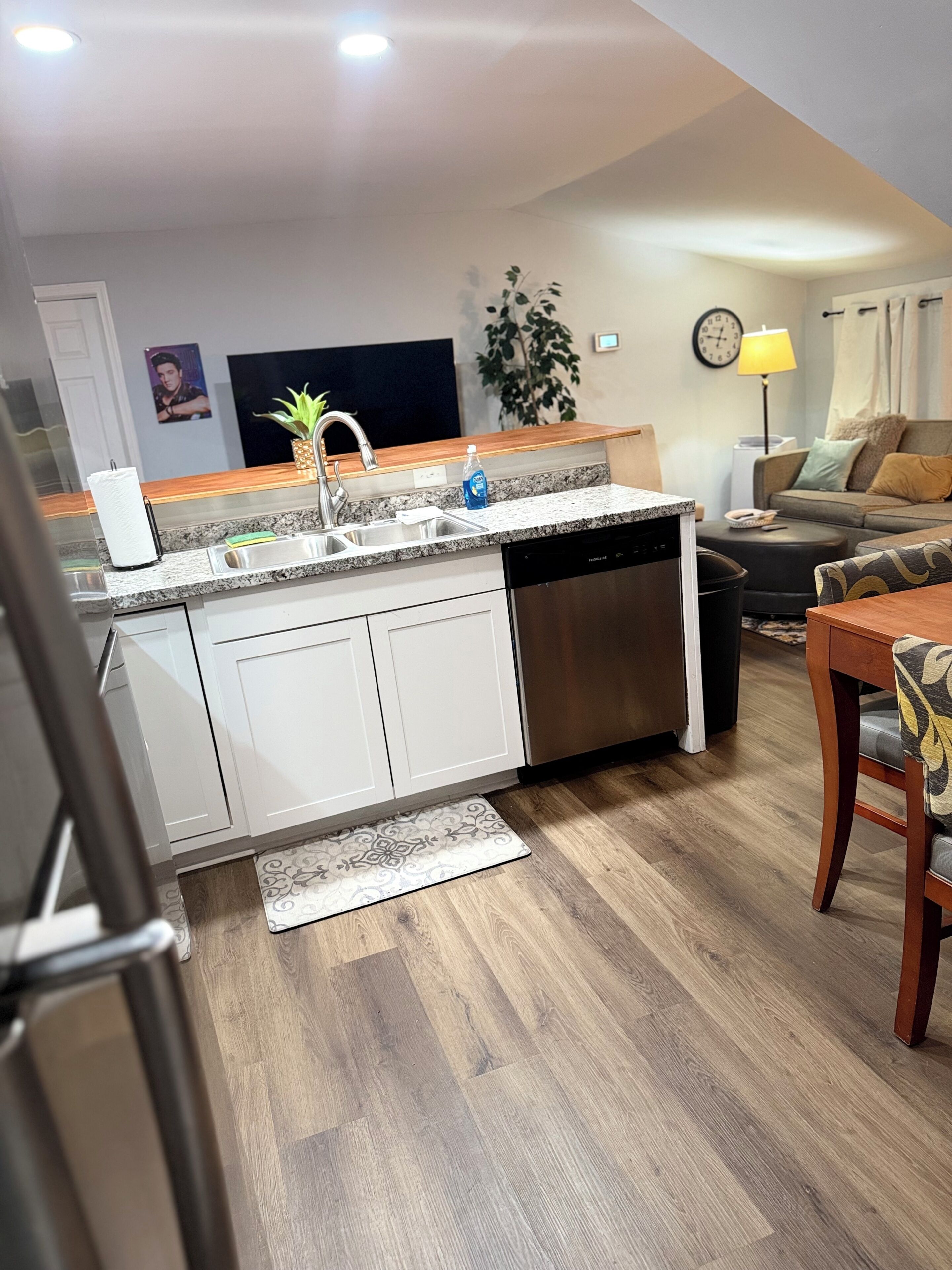 A modern kitchen with a dishwasher, a sink, and a countertop. There is a dining area with a table and chairs.