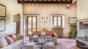 Un salon spacieux avec un haut plafond, une cheminée et une grande fenêtre.