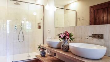 Un bagno moderno con doccia vetrata, due lavabi a vasca, uno specchio e un armadietto in legno.
