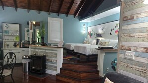 Una sala de estar acogedora con chimenea, un comedor con mesa y sillas, y un dormitorio con cama y decoración en la pared.