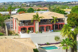 Una casa de dues plantes amb piscina, envoltada de palmeres i vistes a una zona residencial.