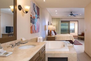 Ein Hotelzimmer mit einem großen Bett, einem eigenen Badezimmer mit einer Badewanne, einem Balkon mit Blick und einem Deckenventilator.