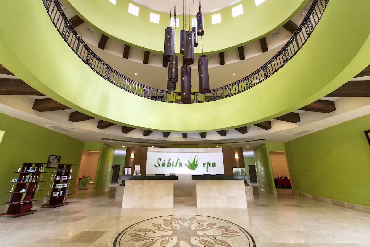 Eine Hotelhalle mit einer zentralen Rezeption, einer Wendeltreppe und einem dekorativen Bodenmuster.