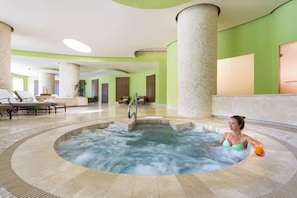 Un espace bien-être comprenant un jacuzzi, des chaises longues et un comptoir d’accueil.