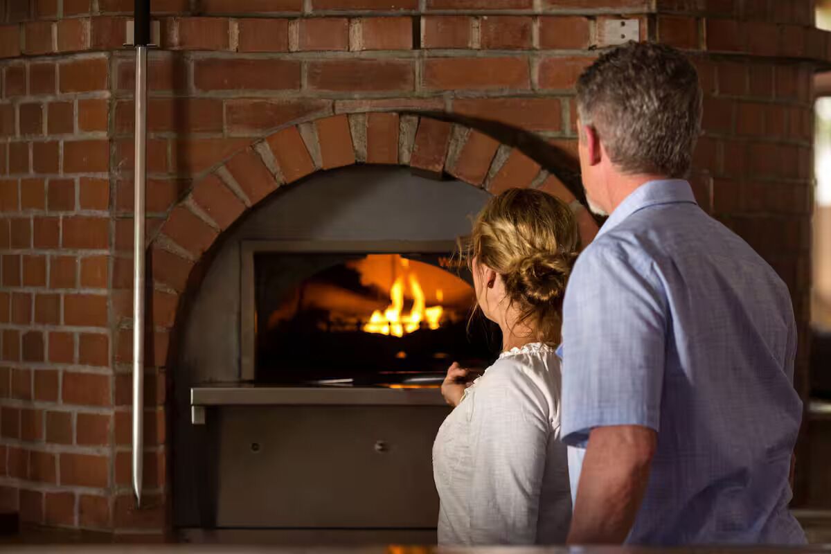 Forn de pizza de rajola amb foc encès a l'interior.