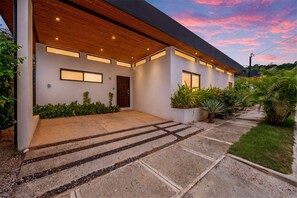 A modern house with a covered porch, a concrete driveway, and a well-maintained garden. - CU11 Private 4BR Oasis-Pool-Guest House-Close to Beach (tamarindo)