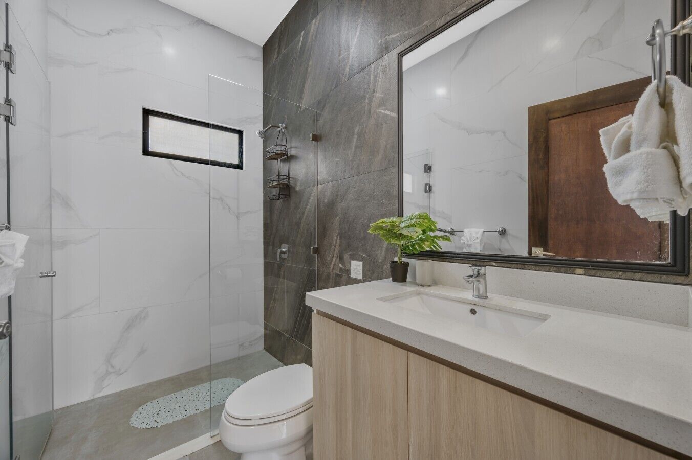 A modern bathroom with a shower, toilet, and vanity.