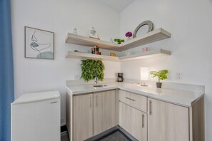Une cuisine moderne avec des meubles de couleur bois clair, un évier encastré et un réfrigérateur compact.