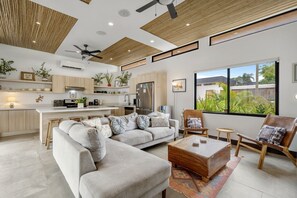 A modern living room with a sectional sofa, a wooden coffee table, and a view of the outdoors through large windows. - CU11 Private 4BR Oasis-Pool-Guest House-Close to Beach (tamarindo)