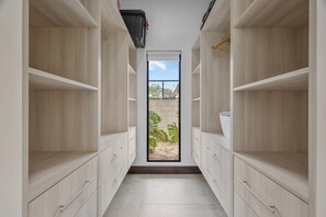 Un couloir étroit, doté de meubles et de tiroirs en bois clair, mène à une porte qui donne sur un jardin.