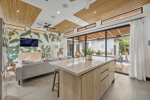 A modern living room with a large island, a sofa, and a television. - CU11 Private 4BR Oasis-Pool-Guest House-Close to Beach (tamarindo)