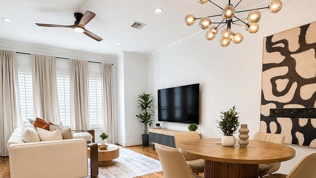 Ein modernes Wohnzimmer mit einer Couch, einem Esstisch mit Stühlen, einem Fernseher und einem Deckenventilator.