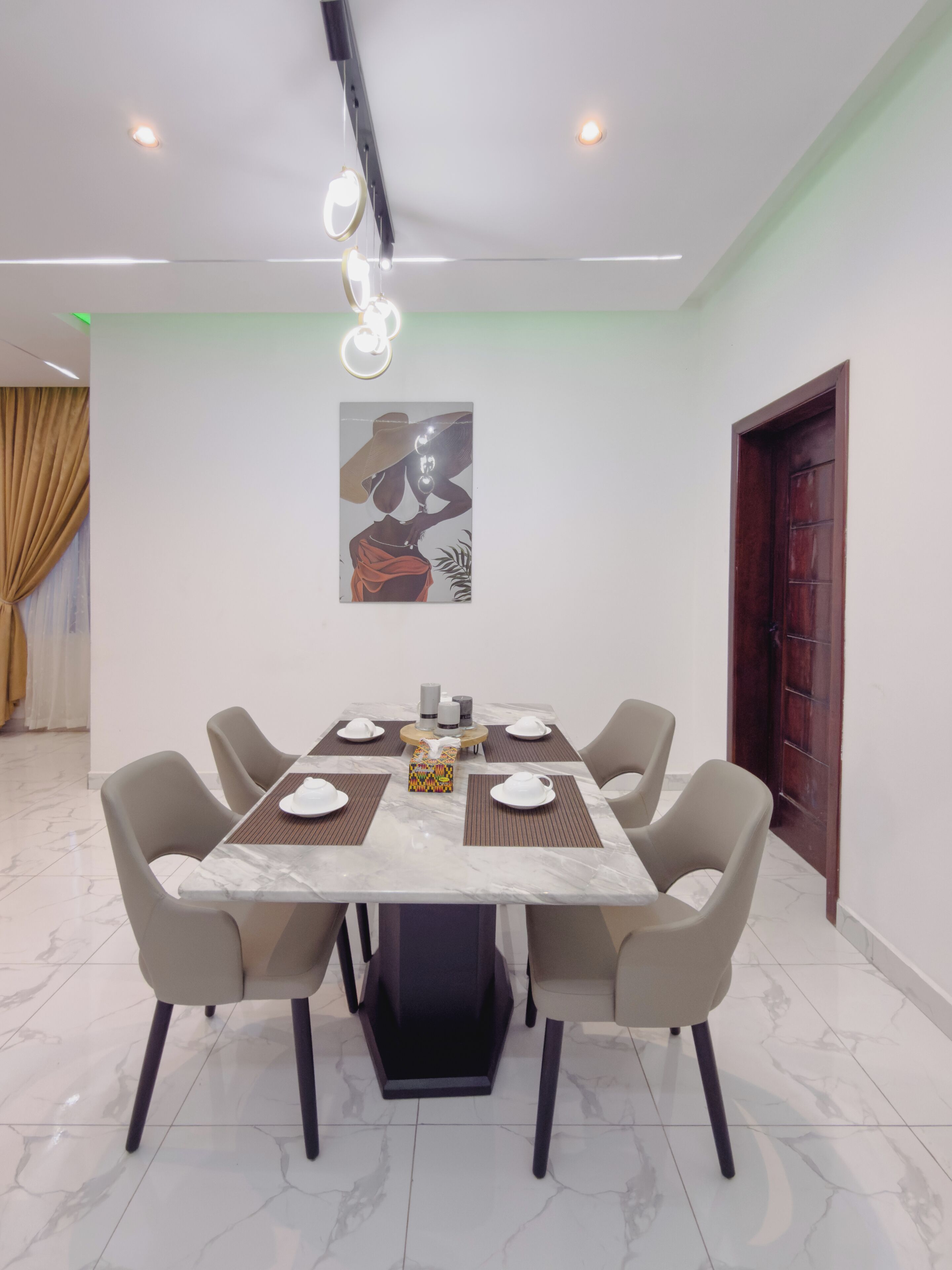 Un coin repas avec une table en marbre, six chaises, un tableau au mur et une porte.