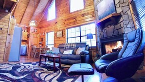 A log cabin interior with a stone fireplace, wooden walls, a dining area, and a cozy seating arrangement. - Hot Tub • Pet Friendly • 12 Min to Blue Ridge (Blue Ridge)