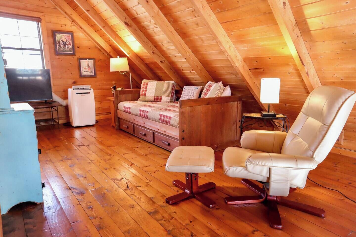 Une pièce mansardée accueillante, avec un lit, une chaise, un bureau et un réfrigérateur.