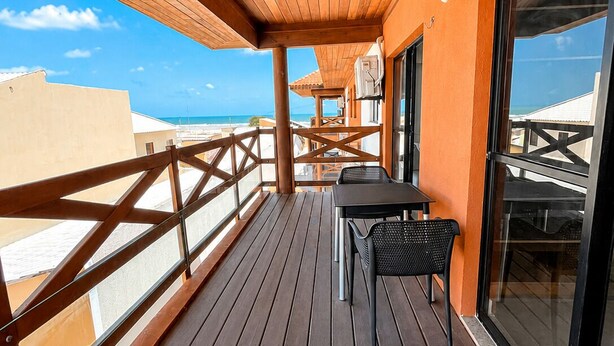 A wooden deck with a table and chairs, overlooking a beach. - Apartment with balcony and sea view, 3 minutes from Atalaia beach. (Luís Correia)