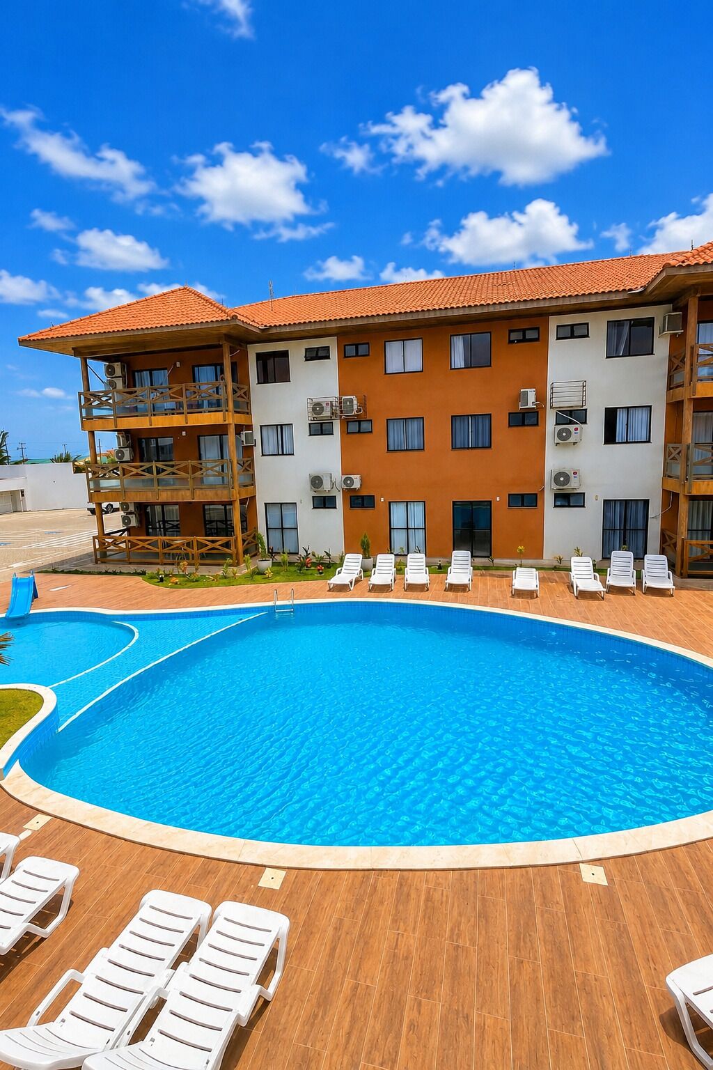 Un hôtel doté d’une piscine, de nombreux balcons et offrant une vue sur un ciel d’un bleu limpide.