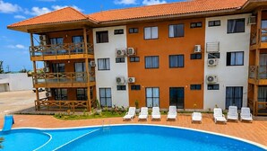 A hotel with a swimming pool, multiple balconies, and a clear blue sky. - Apartment with balcony and sea view, 3 minutes from Atalaia beach. (Luís Correia)