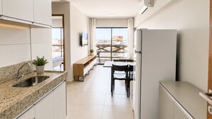 A modern kitchen with a built-in oven, a sink, and a dining area with a bench. - Apartment with balcony and sea view, 3 minutes from Atalaia beach. (Luís Correia)