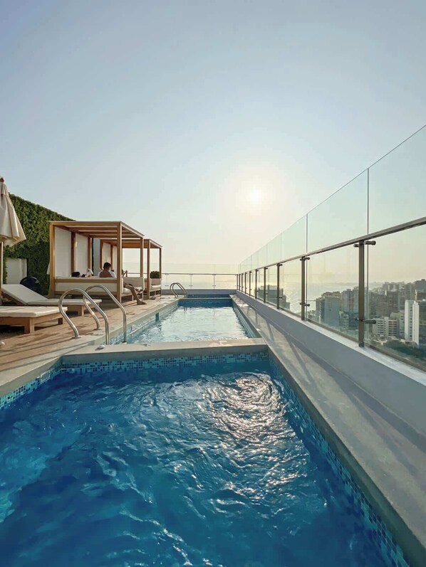A rooftop infinity pool with lounge chairs and a wooden deck area. - Geko | Cozy loft w/ Balcony in Barranco (Barranco)